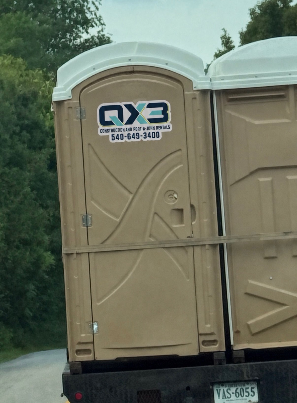QX3 branded standard portable restrooms loaded on a truck bed
